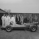 A photo of the Lotus team standing around a vintage car.